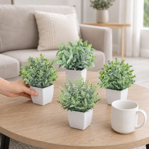 Four mini fake plants displayed on a desk surface
