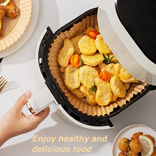 Air fryer basket with food and paper liner inside